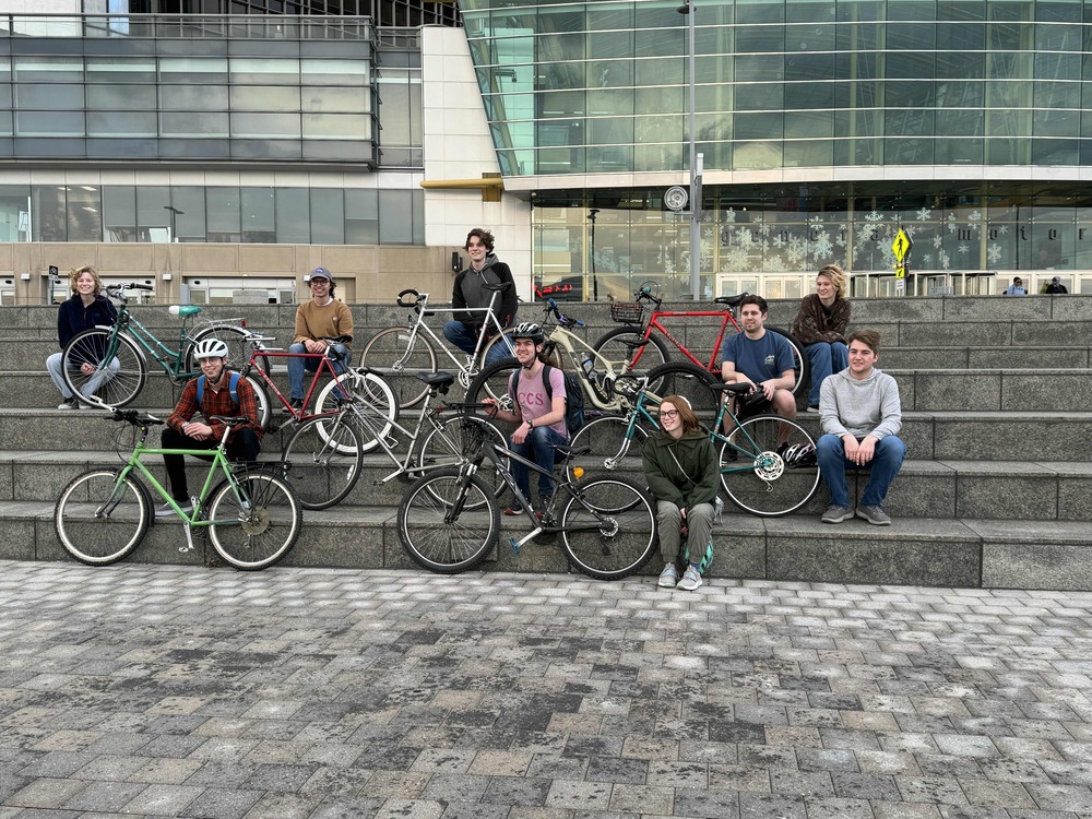 Group photo of my friends and our bicycles on the steps in front of the GM RenCen by the Detroit River.