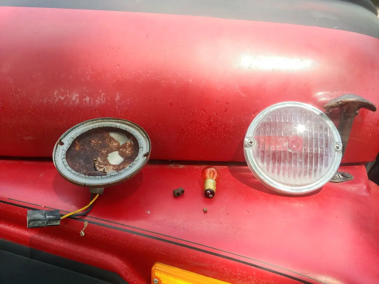 Disassembled turn signal lamp assembly: housing, wire harness, contact that broke off wire, degraded rubber grommet, bulb, and lens cover.