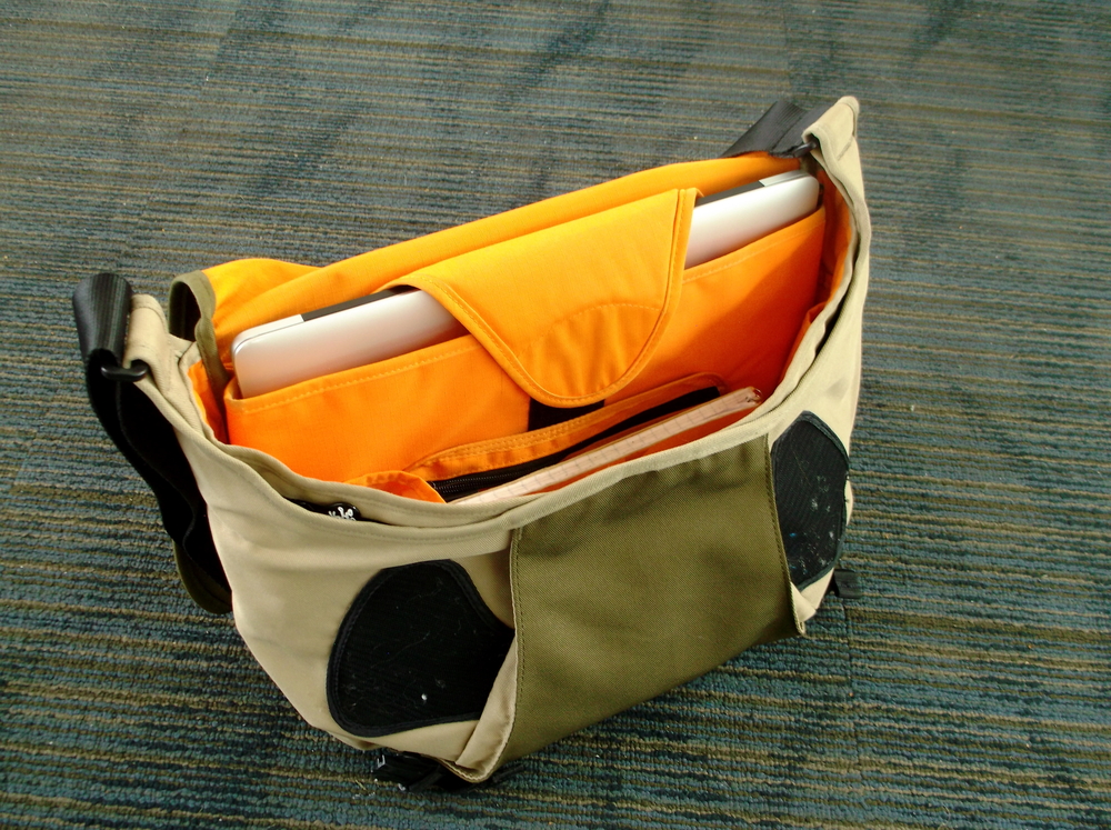 Bag open showing laptop compartment and zipper pockets.