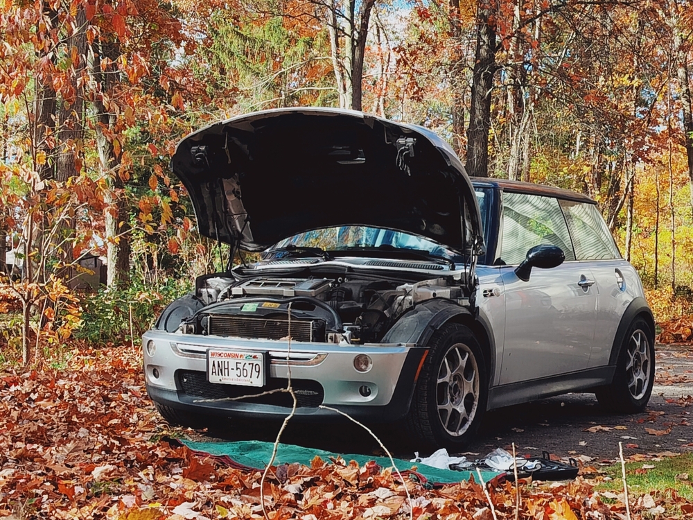 Mini Cooper S R53 with hood up getting oil drained in fall scene.