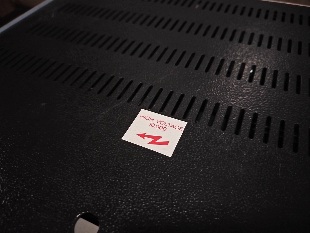 Close up shot of 'High Voltage 10,000V' warning sticker. A holdover from when this used to be a high-voltage scientific power supply.