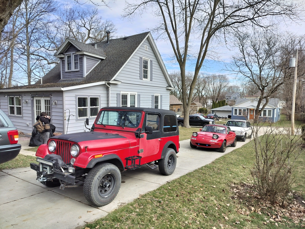 Jeep CJ-7, Volvo 244, Mazda MX-5, and Chevrolet Silverado lined up in the driveway.